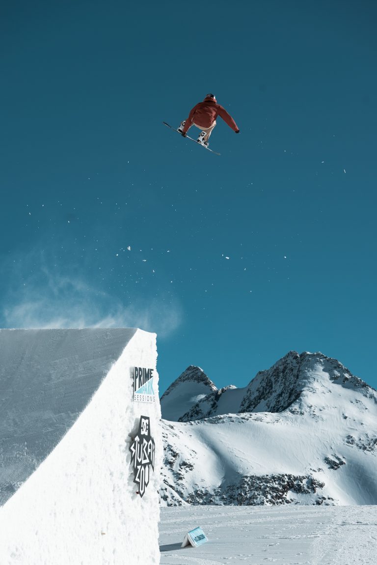 Snowboarder beim Sprung von einer Rampe an einem sonnigen Tag in den Bergen